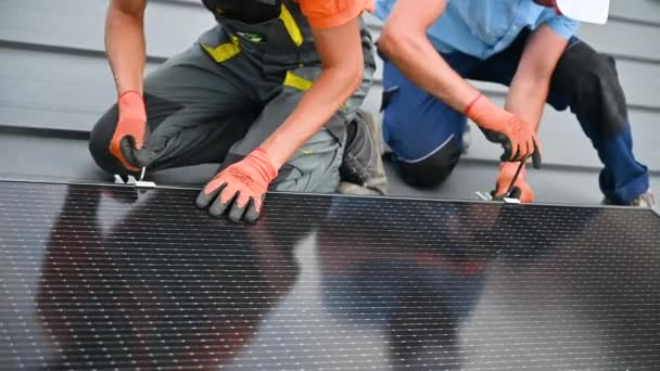 家の屋上に太陽光発電パネルシステムを構築する労働者 屋外の六角キーの助けを借りて太陽電池モジュールを取付ける手袋の男性の技術者の近く 代替エネルギー生成コンセプト — ストック動画