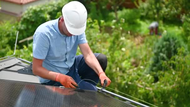 工人在房顶上建造光伏太阳能电池板系统 在户外安装时 头盔工程师观察太阳能组件的均匀性 替代能源和可再生能源的概念 — 图库视频影像