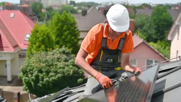 工人在房顶上建造光伏太阳能电池板系统 戴着头盔和手套的男子工程师在室外用六角钥匙安装太阳能组件 可再生能源生产概念 — 图库视频影像