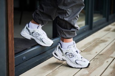 Lviv, Ukrayna - 10 Haziran 2023: uzun yürüyüşler için en iyi ayakkabılar. New Balance 530 spor ayakkabılı bir kadının kesilmiş fotoğrafı. Kız kapıdan çıkıyor..