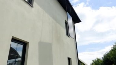Erkek işçiler evin çatısına güneş paneli kuruyor. Kasklı elektrikçiler fotovoltaik güneş modülünü açık havada halatların yardımıyla kaldırıyorlar. Alternatif ve yenilenebilir enerji kavramı.