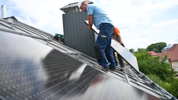 在房顶上建造太阳能电池板系统的工人 两名戴钢盔的男子在室外安装了光电太阳能组件 绿色和可再生能源发电概念 — 图库视频影像