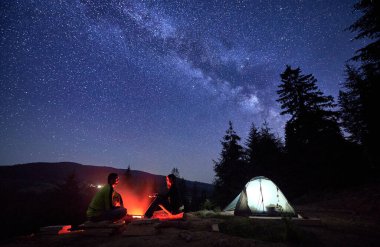 Gece vakti dağlarda, yıldızlı gökyüzünün altında. Erkek ve kadın, korkusuz gezginler, kamp ateşinin titreyen alevleriyle, çadırlarının yanında, Samanyolu 'nun altında,.
