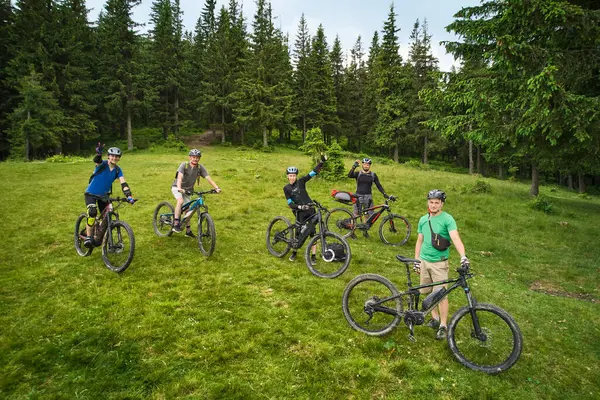 Group of cyclists men riding electric bikes outdoors. Portrait of happy tourists resting on the top of hill, enjoying beautiful mountain landscape. Concept of sport, active leisure and nature.