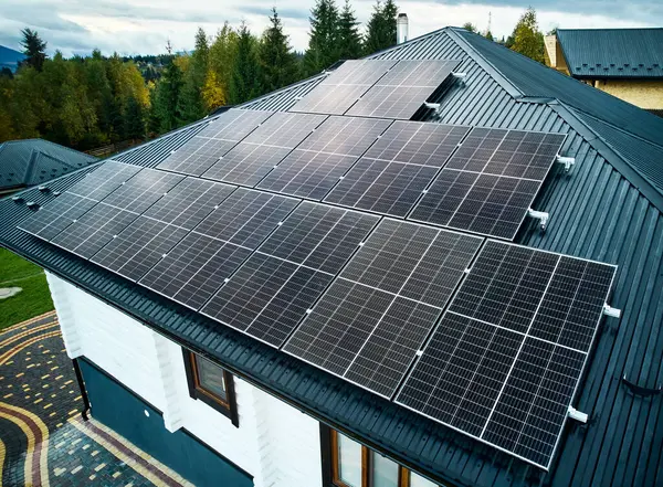 Aerial view of new modern house cottage with solar photovoltaic panel system on roof. Concept of alternative, renewable energy and home autonomy.