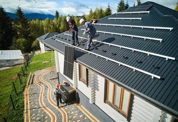 Professionelle Arbeiter Hieven Solarzellen Auf Ein Hausdach Zwei Techniker Mit Stockbild