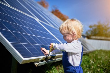 Çocuk güneş panelinin nasıl çalıştığını öğreniyor. Farklı aletlerle ilgilenen küçük bir çocuk. Meraklı çocuk vidayı sıkmaya yardım ediyor..