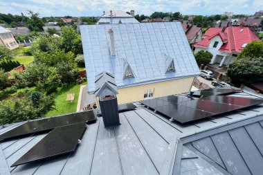 Çatıda fotovoltaik etkiyle elektrik üretmek için güneş panelleri olan bir ev. Çatıda güneş enerjisi sistemi olan bir ev. Alternatif enerji kavramı, özerklik, güç sürdürülebilir kaynaklar.