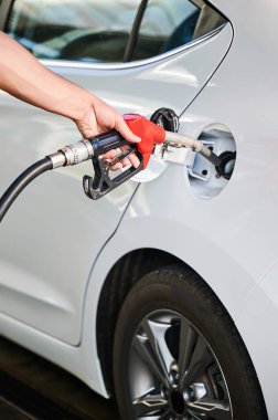 Yakıt ikmali yapan adamın yakın görüntüsü. Şoför kırmızı pompa hortumunu tutuyor ve benzin deposunu dolduruyor. Benzin istasyonundaki arabaya benzin dolduruyorum..