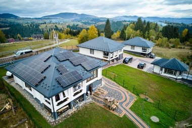 Dağlardaki güneş fotovoltaik panel sistemi çatıda olan yeni modern ev manzarası. Alternatif, yenilenebilir enerji ve ev özerkliği kavramı.