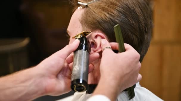 专业理发师剃须侧边的特写照片 紧紧抓住耳朵做直线 使用电动剃须刀工作的合格理发师 — 图库视频影像