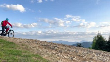 Dışarıda bisiklete binen iki bisikletçi. Erkek turistler dağlarda bisiklet sürüyorlar, kaskları ve sırt çantaları takıyorlar. Spor anlayışı, aktif eğlence ve doğa.