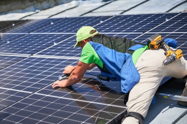 Evin çatısında fotovoltaik güneş paneli inşa eden bir işçi. Ingiliz anahtarının yardımıyla güneş modülü kuran insan mühendisi. Alternatif ve yenilenebilir enerji üretimi kavramı.