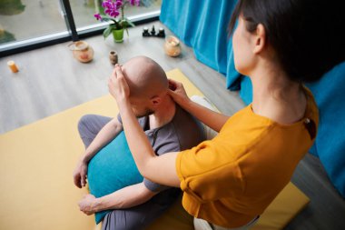 Masör Tayland yogası masajı yapıyor. Kadın terapist erkek hasta için evde geleneksel masaj tedavisi uyguluyor. Kel müşteri paspasın üzerinde oturuyor, meditasyon yapıyor, sakin bir atmosferde el masajının keyfini çıkarıyor..