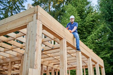 Birleştirici, ormanın yakınına ahşap, iki katlı, çerçeve üzerine inşa edilmiş konut diker. Sakallı, gözlüklü adam çiviyi sert bir şapkayla çakıyor. Günümüz ekolojik yapısının ilkesi.