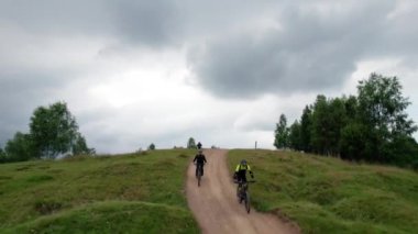 Dışarıda bisiklete binen iki bisikletçi. Erkek turistler dağlarda bisiklet sürüyorlar, kaskları ve sırt çantaları takıyorlar. Spor anlayışı, aktif eğlence ve doğa.