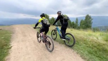 Dışarıda bisiklete binen iki bisikletçi. Erkek turistlerin dağlarda bisiklet sürerken, kask takıp sırt çantaları taktıklarını gördüm. Spor anlayışı, aktif eğlence ve doğa.