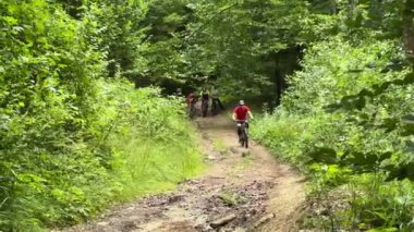 Dışarıda bisiklete binen iki bisikletçi. Erkek turistler dağlarda bisiklet sürüyorlar, kaskları ve sırt çantaları takıyorlar. Spor anlayışı, aktif eğlence ve doğa.