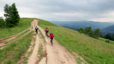 Dışarıda elektrikli bisiklete binen üç bisikletçi. Erkek turistlerin dağlarda bisiklet sürerken, kask takıp sırt çantaları taktıklarını gördüm. Spor anlayışı, aktif eğlence ve doğa.