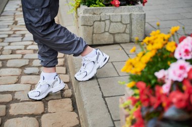 Çiçek tarlasının yanında yürüyen bir kadının kesilmiş fotoğrafı. Aktif hayat için en rahat ayakkabıları giyen kız..