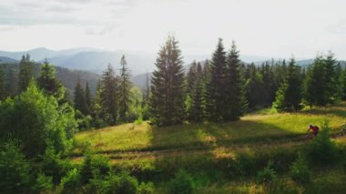 İki bisikletçi gün batımında dışarıda elektrikli bisiklet sürüyor. Erkek turistler dağlarda bisiklet sürüyorlar, kaskları ve sırt çantaları takıyorlar. Spor anlayışı, aktif eğlence ve doğa.