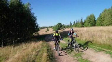 Dışarıda bisiklete binen iki bisikletçi. Erkek turistler dağlarda bisiklet sürüyorlar, kaskları ve sırt çantaları takıyorlar. Spor anlayışı, aktif eğlence ve doğa.