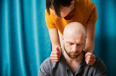 Masseuse making thai yoga massage. Woman therapist doing traditional massage treatment for male patient indoors. Close up view of bald client meditating, enjoying hand massage in calm atmosphere.