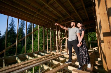 Ormanın yakınındaki dağlarda yaşayan bir adam ve kadın gelecekteki ahşap çerçevelerini inceliyor. Sabahın erken saatlerinde şantiyedeki genç çift. Çağdaş ekolojik yapı kavramı