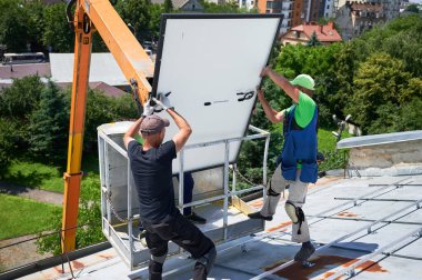 İşçiler vinç kaldırarak evin metal çatısındaki fotovoltaik güneş panelini kaldırıyorlar. Dışarıya fotovoltaik güneş modülleri kuran adamlar. Yenilenebilir enerji üretimi kavramı.
