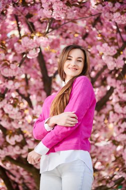 Alerjisi olan bir kadın, bahardaki sezonluk alerjiden zevk alıyor. Baharda çiçek açan sakura ağacının önünde gülümseyen güzel bir kadının portresi. Bahar alerjisi konsepti.