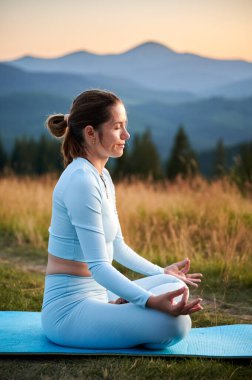 Dağlarda yoga yapan bir kadın, sakin, doğal bir ortamda. Yoga yapan ve akşamları meditasyon yapan bir kadın..