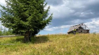 Dışarıda elektrikli dağ bisikleti süren bisikletçi. Erkek turist dağlarda otlak patika boyunca bisiklet sürüyor, başlık ve sırt çantası takıyor. Spor anlayışı, aktif eğlence ve doğa.