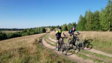 Dışarıda bisiklete binen iki bisikletçi. Erkek turistler dağlarda bisiklet sürüyorlar, kaskları ve sırt çantaları takıyorlar. Spor anlayışı, aktif eğlence ve doğa.