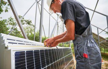 Metal kirişleri güneş panelleri kurmak için mezurayla ölçen bir işçi. İş kıyafetli bir adamın kesilmiş görüntüsü