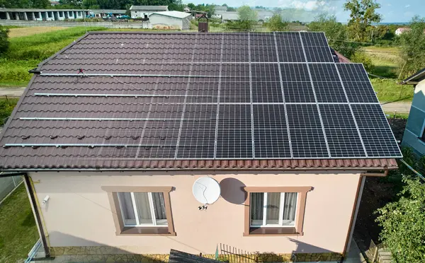 stock image Photovoltaic solar panel fading away and shifting into metal supporting structure. Transition between metal rails and solar modules on roof of house. Concept of alternative energy sources. Aerial view