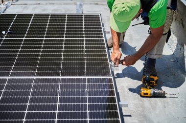 Evin çatısında fotovoltaik güneş paneli inşa eden bir işçi. Güneş modülü döşeyen insan mühendislerine yakın çekim. Alternatif ve yenilenebilir enerji üretimi kavramı.