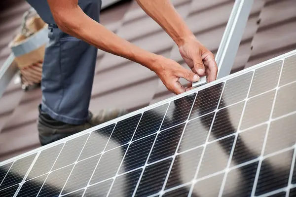 stock image Man worker mounting photovoltaic solar moduls on roof of house. Close up of electrician installing solar panel system outdoors. Concept of alternative and renewable energy.