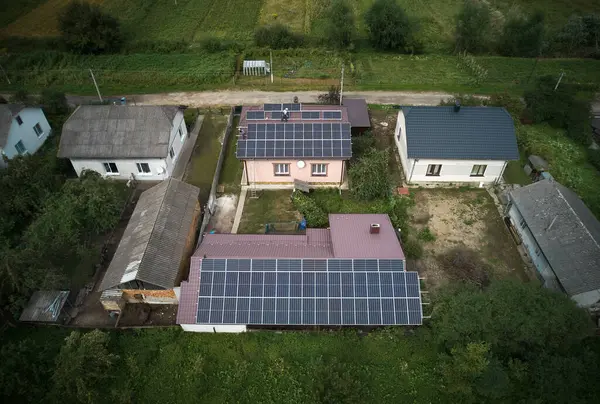 Men installers mounting photovoltaic solar moduls on roof of house. Engineers in helmets installing solar panel system outdoors. Concept of alternative and renewable energy. Aerial view.