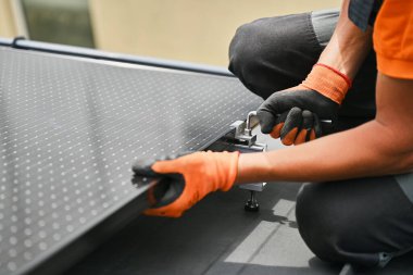 Evin çatısında fotovoltaik güneş paneli inşa eden bir işçi. Eldiven takan insan mühendislerine yakın çekim yapın. Güneş modülü takın. Dışarıdaki hex anahtarının yardımıyla. Yenilenebilir enerji üretimi kavramı.