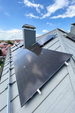Çatıda fotovoltaik etkiyle elektrik üretmek için güneş panelleri olan bir ev. Çatıda güneş enerjisi sistemi olan bir ev. Alternatif enerji kavramı, özerklik, güç sürdürülebilir kaynaklar.