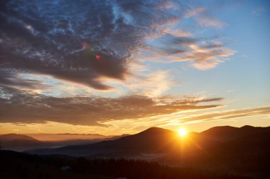 Güneş tepelerin ardından yükselir, gökyüzünde dramatik bulutlarla dolu altın bir parıltı yayar. Aşağıdaki vadi sisle aydınlanıyor, sabahları huzur ve resim manzarasını geliştiriyor..