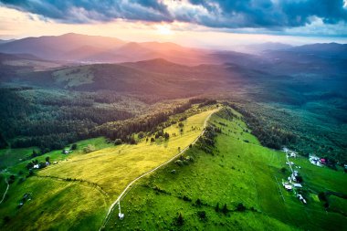 Günbatımında Ukrayna 'nın büyüleyici manzarası, yuvarlanan yeşil tepeler, geniş ormanlar ve dağınık çiftlik evleri. Ilık ışık manzarayı yıkıyor, dingin ve görkemli bir atmosfer yaratıyor..