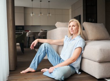 Dairesinde kanepenin yanında oturan kadının portresi. Gündelik giysiler içinde güzel bir kadın başka tarafa bakıyor..