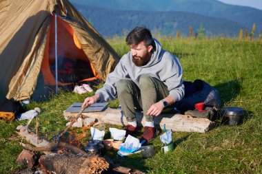Sabahları iki çadırı olan manzaralı dağ kampı. İki kampçı, bulutsuz gökyüzünün altında yuvarlanan dağların huzurlu manzarasının keyfini çıkarıyorlar. Resimli gündoğumu manzarası, huzurlu ve rahat bir açık hava deneyimi yaratıyor..