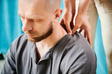 Masseuse making thai yoga massage. Woman therapist doing traditional massage treatment for male patient indoors. Close up view of bald client meditating, enjoying hand massage in calm atmosphere.