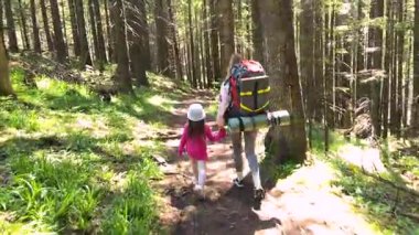 Anne ve küçük kızı güneş ışığıyla aydınlanan ormanda el ele yürüyorlar. Kadın kamp malzemeleriyle birlikte büyük bir sırt çantası taşırken, çocuk hevesle onu takip ediyor. Uzun ağaçlar ve yemyeşil patikalar..