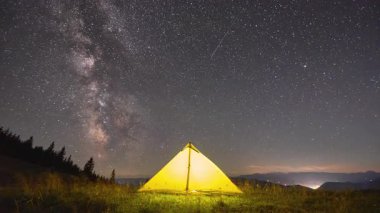 Zaman aşımı. Yıldızlarla ve Samanyolu 'yla dolu büyüleyici gece göğünün altında parlayan sarı çadır. Çimenli tarlalar ve gölgeli çam ağaçlarıyla çevrili. Doğada kamp yapmanın güzelliği ve sükuneti..