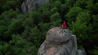 Ukrayna 'daki Karpat Dağları' ndaki Dovbush Kayalıkları 'ndaki kaya oluşumunun havada görünen görüntüsü. Güneş batıyor, yemyeşil orman, uzak tepeler üzerine ılık bir parıltı saçıyor, nefes kesici bir manzara yaratıyor..