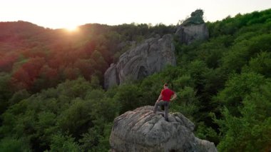 Ukrayna 'daki Karpat Dağları' ndaki Dovbush Kayalıkları 'ndaki kaya oluşumunun havada görünen görüntüsü. Güneş batıyor, yemyeşil orman, uzak tepeler üzerine ılık bir parıltı saçıyor, nefes kesici bir manzara yaratıyor..