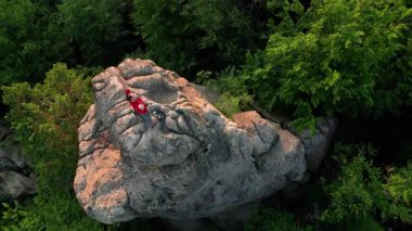 Ukrayna 'daki Karpat Dağları' ndaki Dovbush Kayalıkları 'ndaki kaya oluşumunun havada görünen görüntüsü. Güneş batıyor, yemyeşil orman, uzak tepeler üzerine ılık bir parıltı saçıyor, nefes kesici bir manzara yaratıyor..